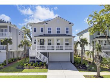 Stunning two-story beach home featuring a classic white exterior, a charming front porch, and lush tropical landscaping at 2194 Cultura Cir, Mount Pleasant, SC 29466