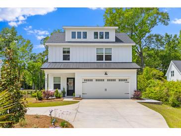 Charming two-story modern farmhouse exterior with black roof, white siding, and a well manicured front yard at 481 Woodland Shores Rd, Charleston, SC 29412