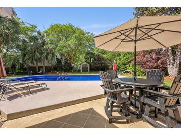 Backyard pool featuring outdoor seating and a lush green area with mature trees, ideal for entertaining at 5401 Diston Court, North Charleston, SC 29420