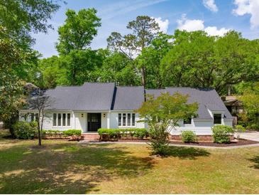 Charming one-story home with a well-manicured lawn and a classic black front door at 667 Shortwood St, Charleston, SC 29412