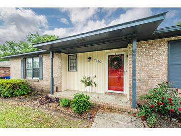 Charming covered front porch with brick accents, updated paint, and well-manicured landscaping at 7655 Ovaldale Dr, North Charleston, SC 29418