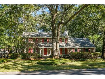 Charming two-story brick home with mature trees and red shutters on a sunny day at 112 Huckleberry Ln, Summerville, SC 29485