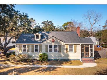 Charming home featuring light yellow siding, gray shingles, a brick chimney, and a cozy screened in porch at 2178 Fort Pemberton Dr, Charleston, SC 29412