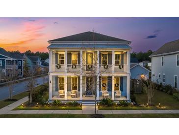 Charming two-story home with a double porch, white columns and blue shutters at dusk at 282 Great Lawn Dr, Summerville, SC 29486
