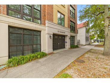 Elegant condominium building entrance featuring a gated entry and a classic brick and stucco facade at 33 Calhoun St # 123, Charleston, SC 29401