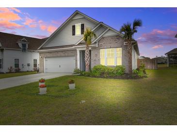 Charming single-Gathering home boasts a well-manicured lawn and features a mix of brick and siding at dusk at 349 Long Pier St, Summerville, SC 29486