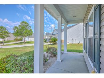 Inviting covered front porch with white columns and views of the well-maintained front yard and landscaping at 7477 Painted Bunting Way, Hanahan, SC 29410