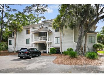 A bright, multi-story condo featuring a stairway, balcony, mature trees, and convenient parking at 856 Club Cottage Rd, Edisto Beach, SC 29438