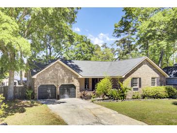 Charming brick home featuring a two-car garage, manicured lawn, and mature trees offering curb appeal at 113 Dove Ln, Summerville, SC 29485