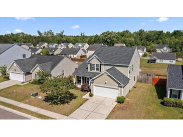 Inviting two-story home featuring a well-manicured lawn, attached two-car garage, and a charming covered front porch at 144 Marinella Dr, Goose Creek, SC 29445