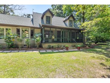 Charming home featuring a screened-in porch and a beautifully landscaped front yard, ideal for outdoor enjoyment at 2144 Pinopolis Rd, Pinopolis, SC 29469