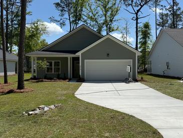 Charming single-story home with a two-car garage, well-manicured lawn, and a concrete driveway at 3218 Pinewood Dr, Ladson, SC 29456