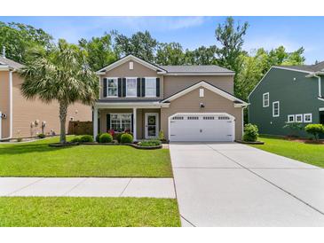 Charming two-story home featuring a well-manicured lawn, a two-car garage, and a welcoming front porch with red chairs at 5451 Kings River Dr, North Charleston, SC 29420