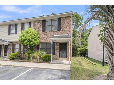 Charming brick townhome featuring black shutters, a covered entrance, and well-maintained landscaping at 6260 Brandt St # 4-D, North Charleston, SC 29406