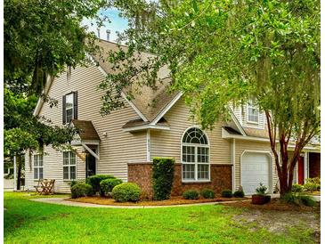 Charming two-story home with tan siding, brick accents, manicured lawn and mature landscaping provides great curb appeal at 8624 Grassy Oak Trl, North Charleston, SC 29420