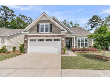 Charming single-story home with a two-car garage, stone accents, manicured lawn, and a welcoming front porch at 1011 Old Field Dr, Summerville, SC 29483