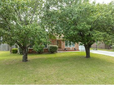 Charming brick home featuring mature trees, green lawn, and a welcoming entrance with a driveway at 103 Winston Way, Goose Creek, SC 29445