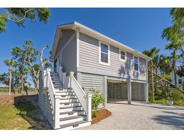 Beautiful two-story coastal home with gray siding, white trim, and an elevated foundation with covered parking at 123 Jungle Rd, Edisto Island, SC 29438