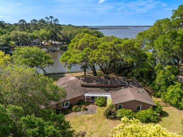 Stunning waterfront home with lush trees, gorgeous landscaping and a charming pergola-covered entrance at 1405 S Edgewater Dr, Charleston, SC 29407
