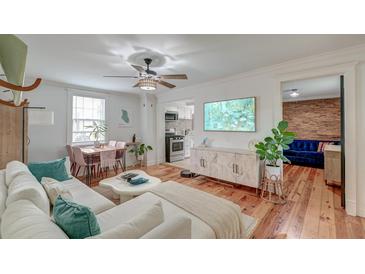 Bright living room featuring hardwood floors, ceiling fan, and open access to the kitchen and dining areas at 3.5 Kracke St # C, Charleston, SC 29403