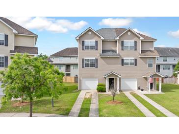 Charming townhome featuring a two car garage, well-maintained lawn, and inviting front entrance at 4209 Climbing Tree Ct, Charleston, SC 29414