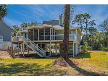 Beautiful exterior view of raised house featuring a screened porch and lush landscaping at 60 Rice Ln, Edisto Beach, SC 29438