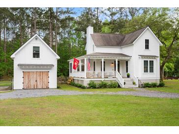 Charming two-story white home with a detached garage and a welcoming front porch at 6373 Farm House Rd, Ravenel, SC 29470