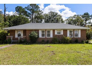 Charming brick home with a well-maintained lawn and traditional white-framed windows and shutters at 809 N Magnolia St, Summerville, SC 29483