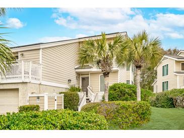 Charming coastal home featuring lush landscaping, palm trees, and a welcoming entryway at 9 Fairway Dunes Ln, Isle of Palms, SC 29451