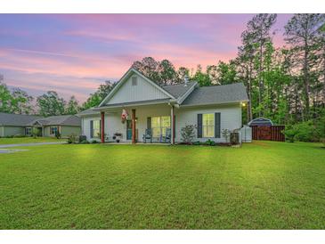 Charming single-story home featuring a covered porch with rocking chairs and lush green lawn at 229 Twin Lake Dr, Summerville, SC 29483