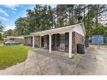 Charming brick home with covered porch and decorative chairs offers a cozy welcome at 317 Dorchester Manor Blvd, North Charleston, SC 29420