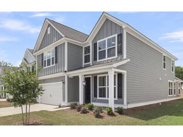 Charming two-story home featuring a well-maintained lawn, gray siding, and a two-car garage at 319 Abercom Place Dr, Moncks Corner, SC 29461