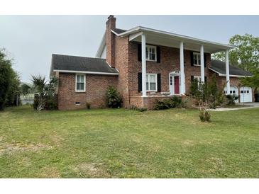 Beautiful brick home featuring a front porch with stately white columns and a well-manicured lawn at 36 Forde Row, Charleston, SC 29412