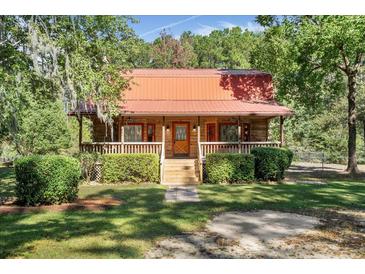 Charming log cabin with a covered porch and neatly manicured landscaping at 398 W Fisher Rd, Summerville, SC 29483