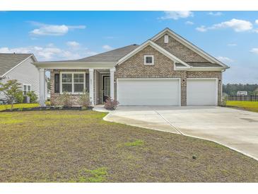 Charming brick home featuring a two-car garage and well-manicured front yard at 431 Canal Crossing Way, Huger, SC 29450