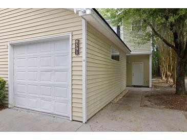 A one-car garage is attached to this home with a door to a separate entrance and neutral siding at 4591 Great Oak Dr, North Charleston, SC 29418