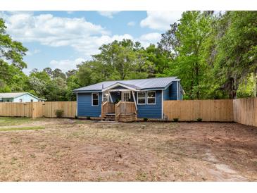 Charming blue home featuring a metal roof, wooden porch, and new wooden fence at 6146 Chisolm Rd, Johns Island, SC 29455