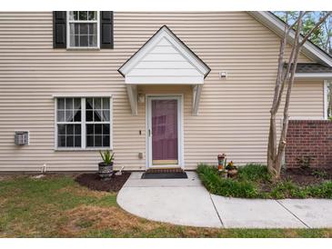 Inviting home entrance featuring a covered front door, neutral siding, and charming landscaping at 8651 Grassy Oaks Trl, North Charleston, SC 29420