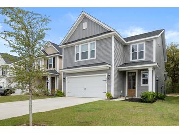 Charming two-story home with a well-manicured lawn and a two-car garage with gray wood-look siding at 8654 Windsor Hill Blvd, North Charleston, SC 29420