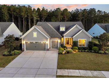 Beautiful single-story home featuring a three-car garage, manicured lawn, and inviting entrance at 128 Camelia Park Ln, Summerville, SC 29486