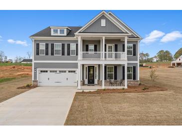 Two-story home featuring a two-car garage, a welcoming front porch, and sleek black shutters against gray siding at 164 Seaton Street, Summerville, SC 29486