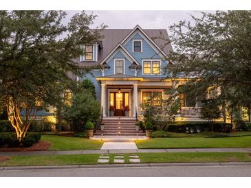 Charming two-story blue home with inviting front porch, manicured lawn, and mature trees at 187 Ithecaw Creek St, Daniel Island, SC 29492