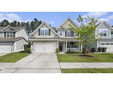 Charming two-story home with a well-maintained lawn, a two-car garage, and a cozy front porch at 317 Whispering Breeze Ln, Summerville, SC 29486