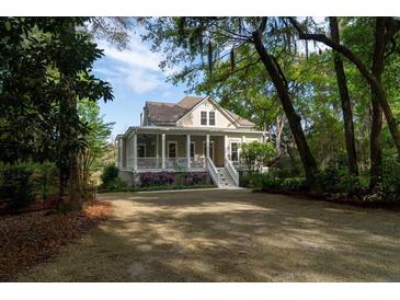 Charming home featuring a welcoming porch and landscaped front yard with mature trees at 8374 Chisolm Plantation Rd, Edisto Island, SC 29438