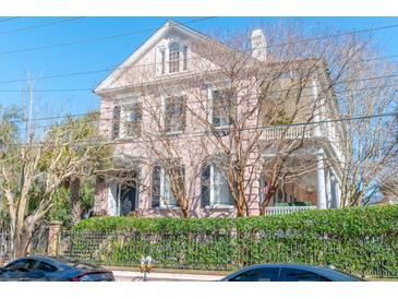 Elegant Charleston home with a pink facade, wrought iron fence, and beautiful architectural details at 192 Ashley Ave # C, Charleston, SC 29403