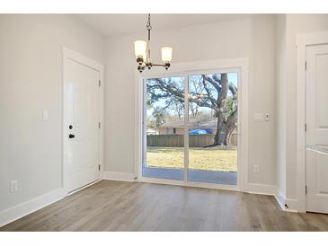 Bright dining area features a sliding glass door to the backyard and modern light fixture at 2606 Bennett Yard Rd, North Charleston, SC 29405