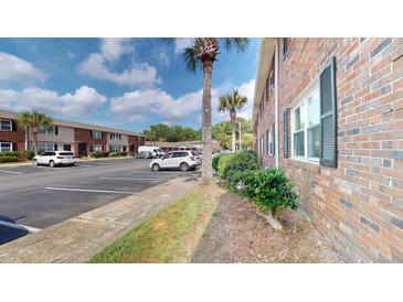 Exterior view of a brick apartment building with ample parking spaces and partial tree coverage at 415 Parkdale Dr # 2F, Charleston, SC 29414