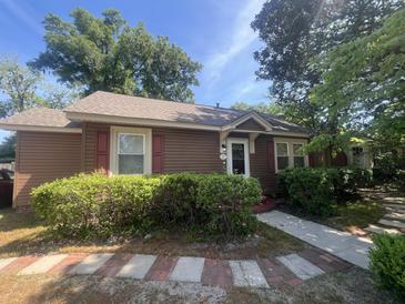 Charming single-story home featuring brown siding, red shutters, and lush landscaping at 117 Weiters St, Walterboro, SC 29488