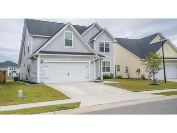 Charming two-story home featuring a well-manicured lawn and attached two-car garage, exuding curb appeal at 124 Long Trail Way, Moncks Corner, SC 29461