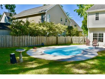 Backyard pool with a well-manicured lawn and a wooden fence providing privacy at 132 E Hartwick Ln, Goose Creek, SC 29445